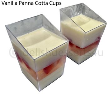 Two clear cups filled with vanilla panna cotta and fruit layers.