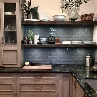 Casual dynamic kitchen with rustic floating shelves, blue glass backsplash, taupe staines wood cabin