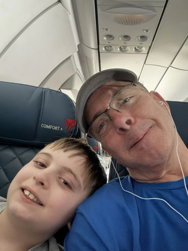 A man and a boy smiling inside an airplane.