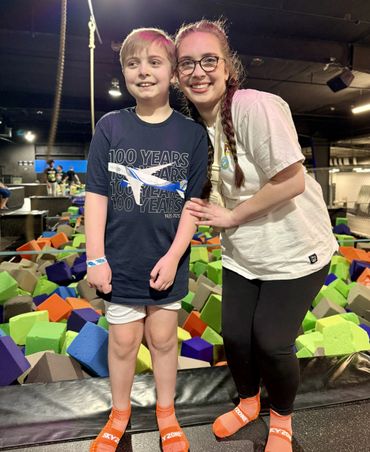 Smiling woman and boy at indoor trampoline park with colorful foam pit.