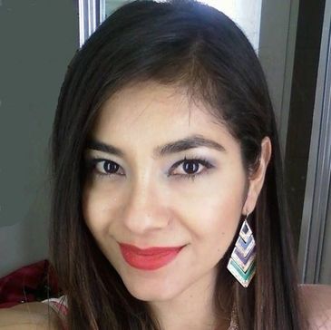 Young woman smiling with bold earrings and red lipstick.