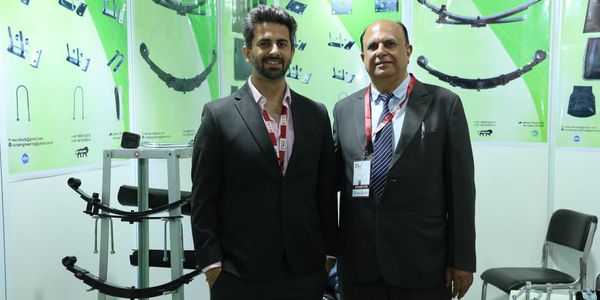 Two men in suits at an engineering products exhibition booth.