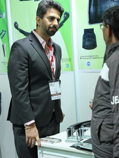Two men discussing mechanical parts at an exhibition booth.