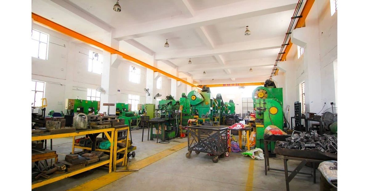 A spacious, well-lit industrial workshop with green machinery and yellow workbenches.