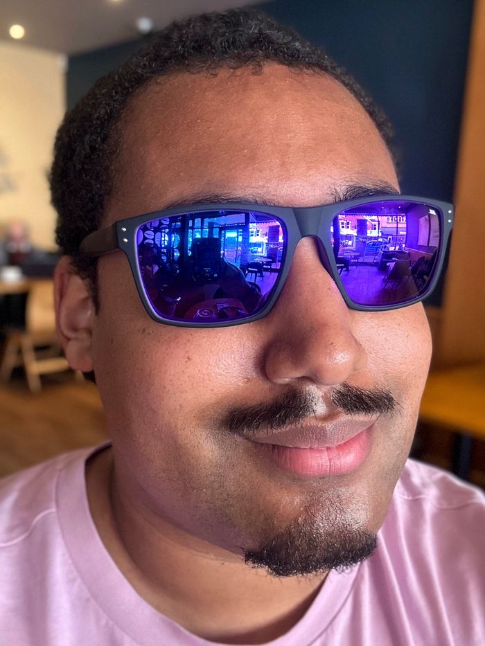 A recent selfie of Mystery Ezekude wearing violet-tinted sunglasses in a cafe in April 2024.