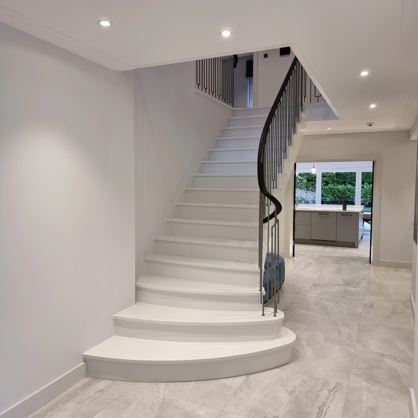 Curved stone staircase with slim metal balustrade in a bright hallway