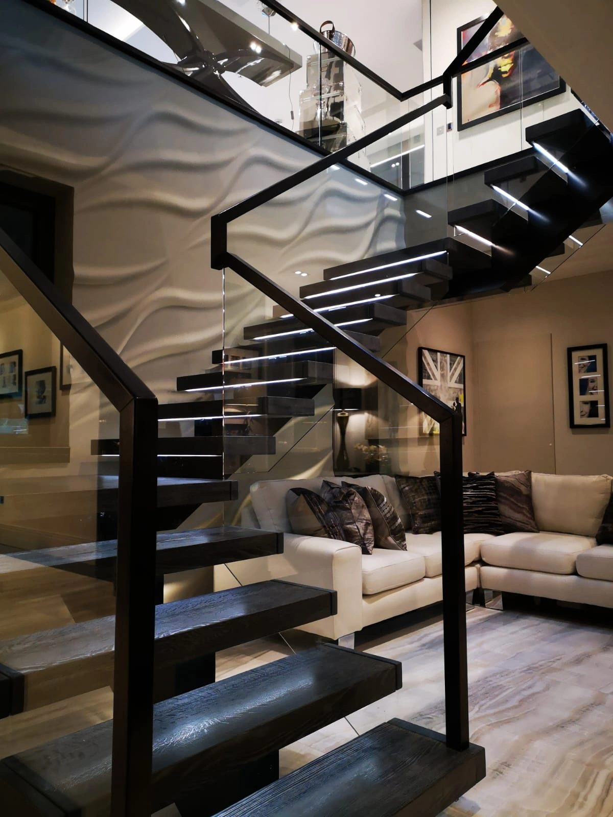 Blackened steel open-tread staircase with structural glass balustrade in a private residence