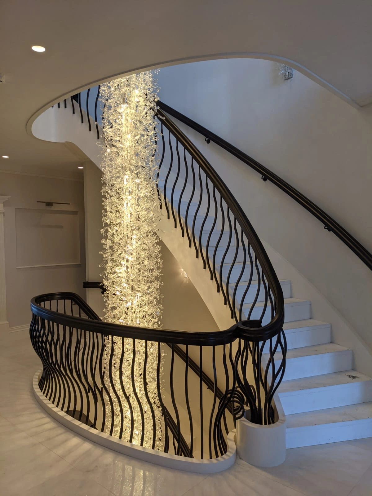 Curved staircase with a full-height chandelier in a private residence