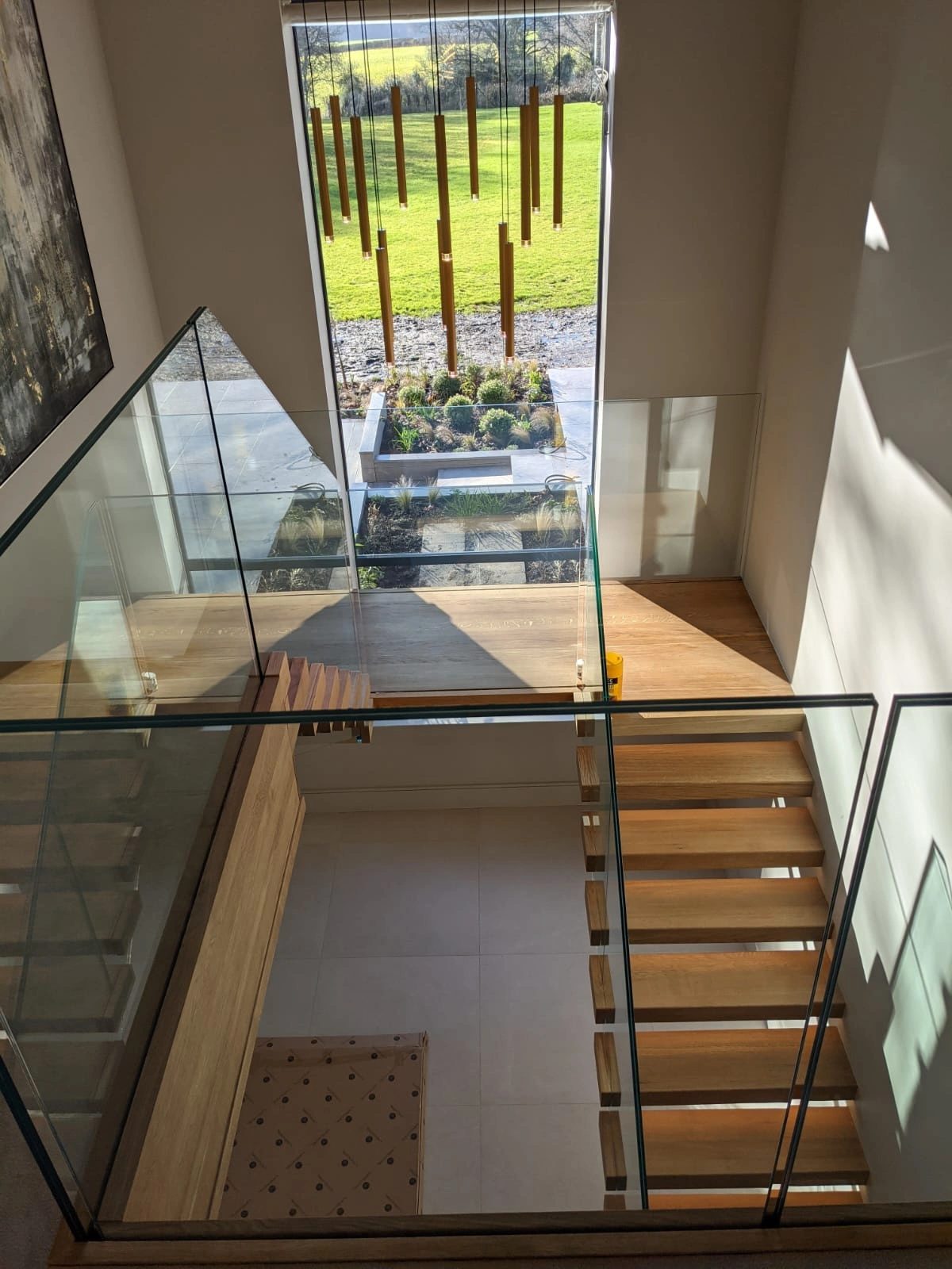 Galleried void with frameless glass balustrade overlooking a garden