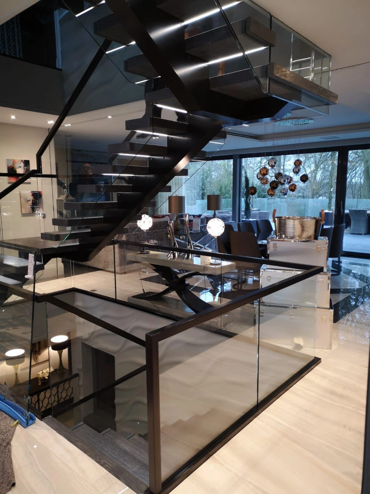 Steel and glass staircase rising through a full-height glazed atrium