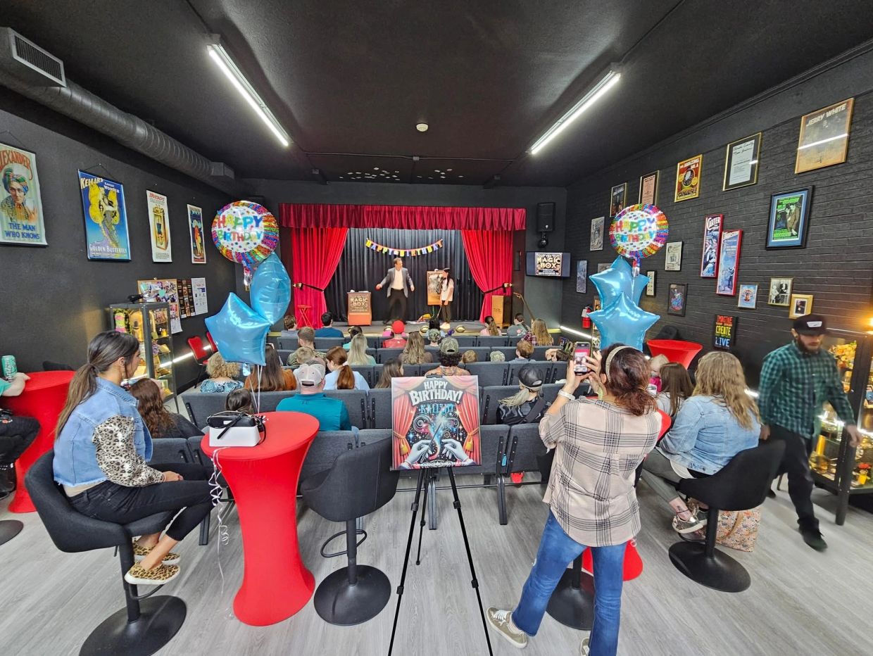 Birthday celebration with magic show on stage.