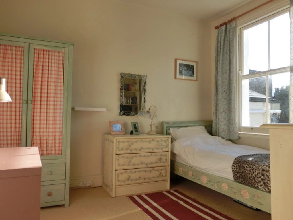 Cozy bedroom with vintage floral furniture and soft natural light.