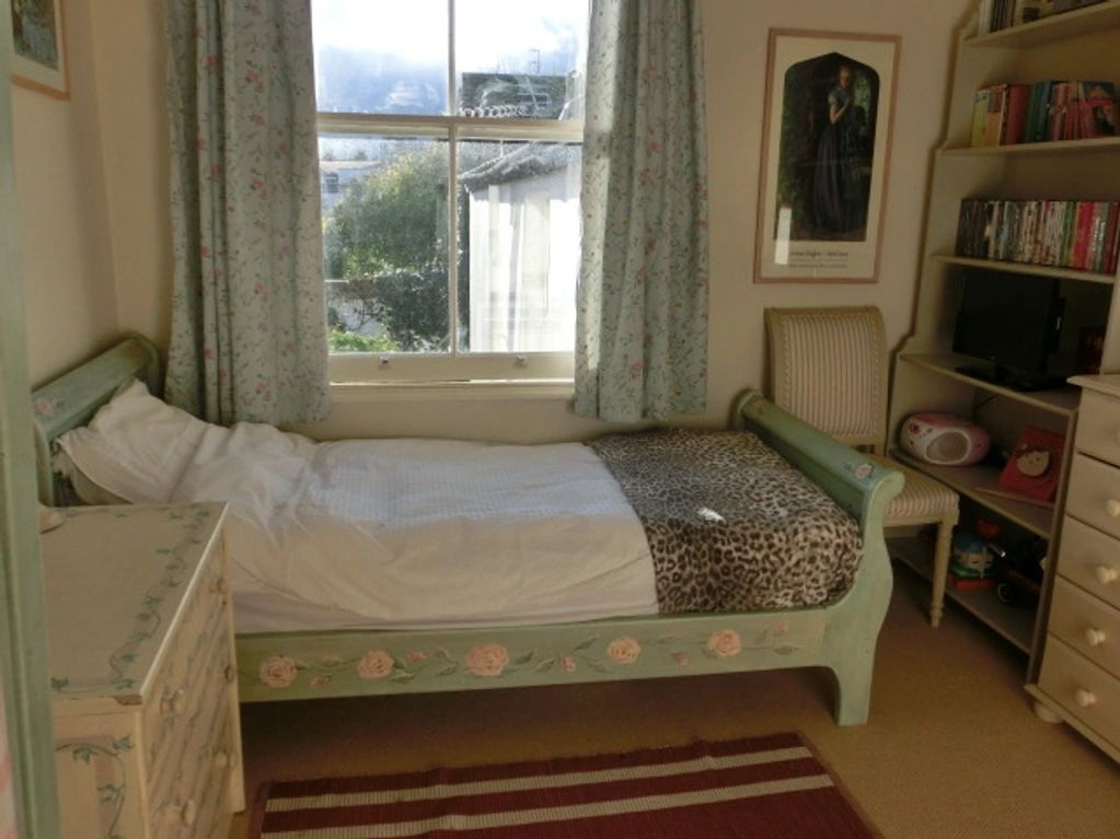 Cozy vintage bedroom with floral curtains and painted furniture.