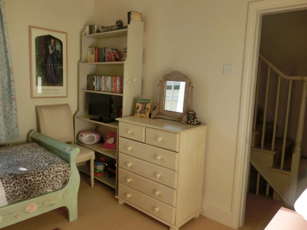Cozy bedroom corner with vintage furniture and a small TV on a bookshelf.