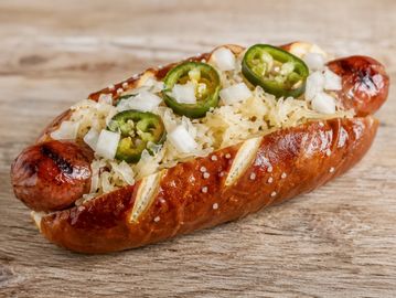 Grilled sausage in a pretzel bun with sauerkraut and jalapenos.