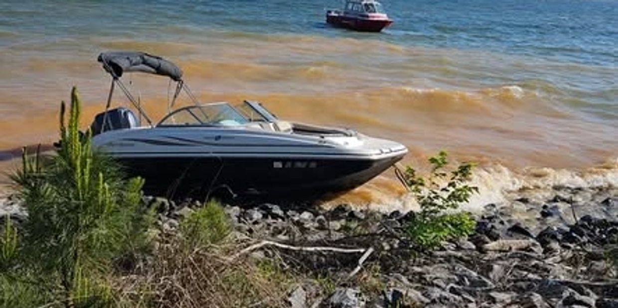 A motorboat docked on a rocky shore with orange-tinted water.