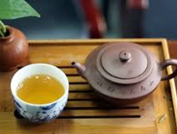 Traditional teapot and cup on a wooden tray.
