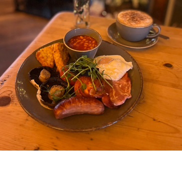 A full English breakfast with coffee on a wooden table.