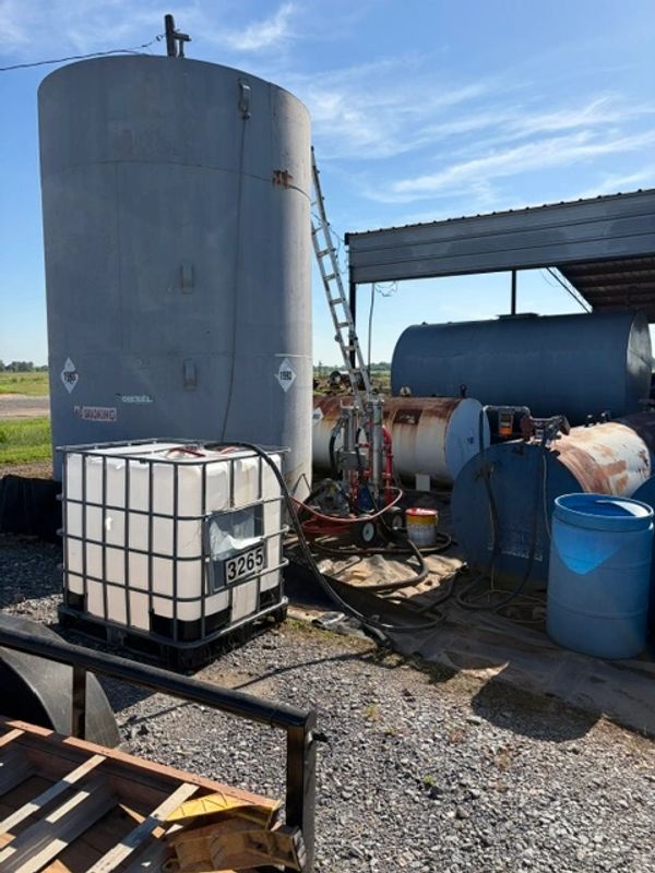 Industrial fuel and chemical storage tanks outdoors under blue sky.