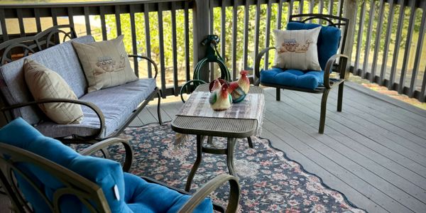 Cozy porch seating with blue cushions, decorative pillows, and a patterned rug.