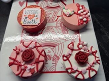 Decorative pink and red love-themed desserts on a white plate.
