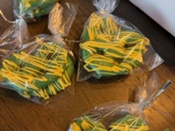 Heart-shaped cookies decorated with green and yellow icing, individually packaged in clear plastic bags.