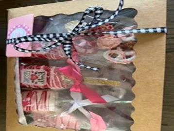 Box of decorated pink and white sweets tied with black and white ribbon.