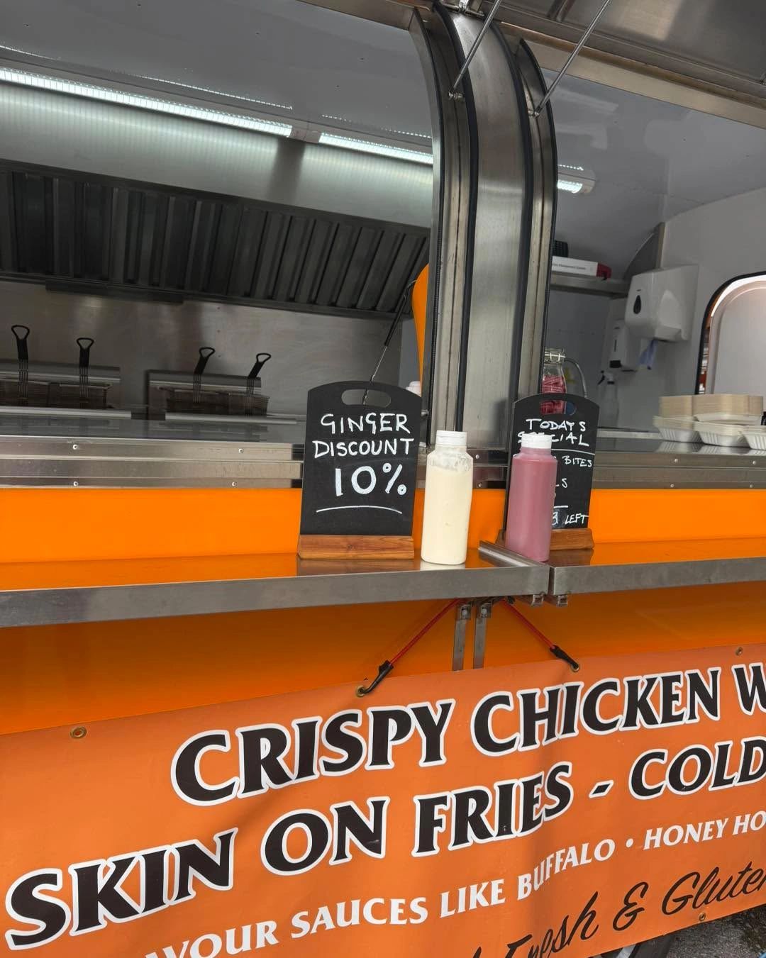 The Ginger Wingman serving hatch, sauces lined up on the counter and the menu board behind