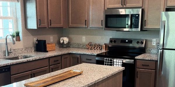 Modern kitchen with granite countertops and wooden cabinets.