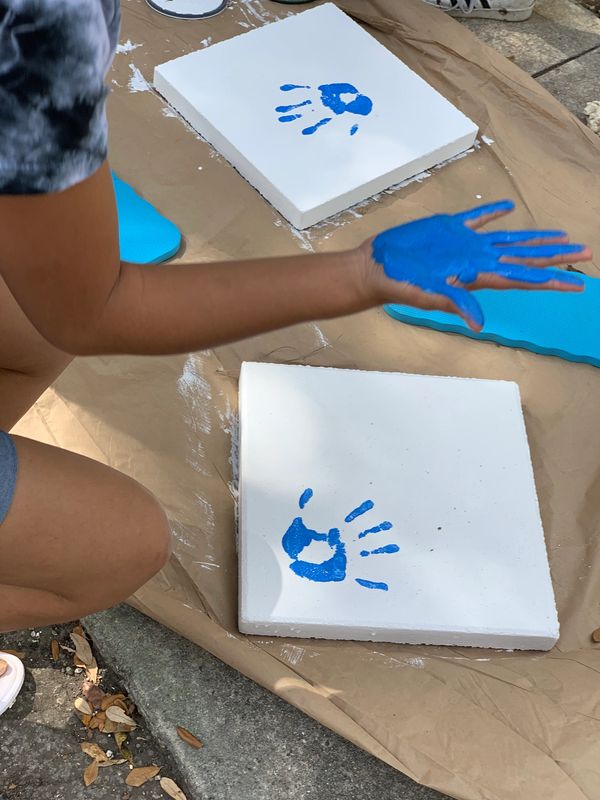 Person making blue handprints on white canvases outdoors.