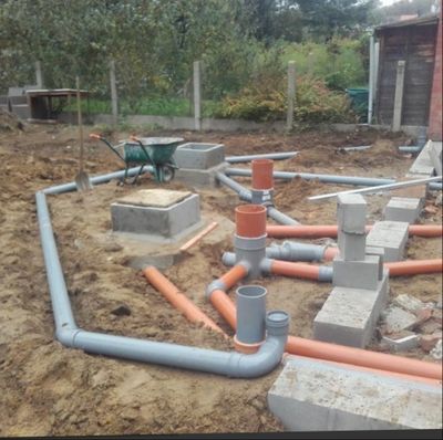 Construction site with plumbing pipes laid out in soil.