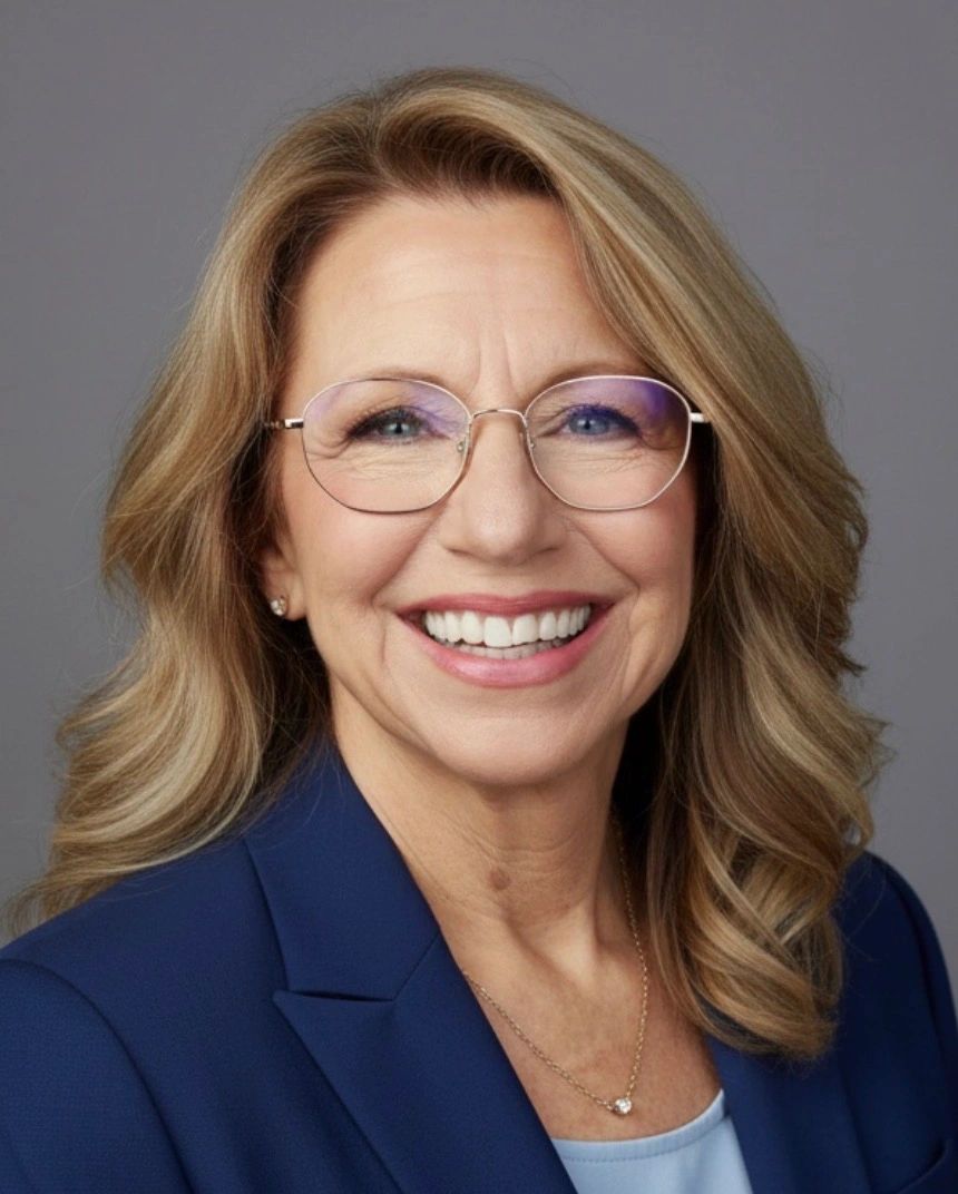 Smiling woman with glasses wearing a blue blazer.