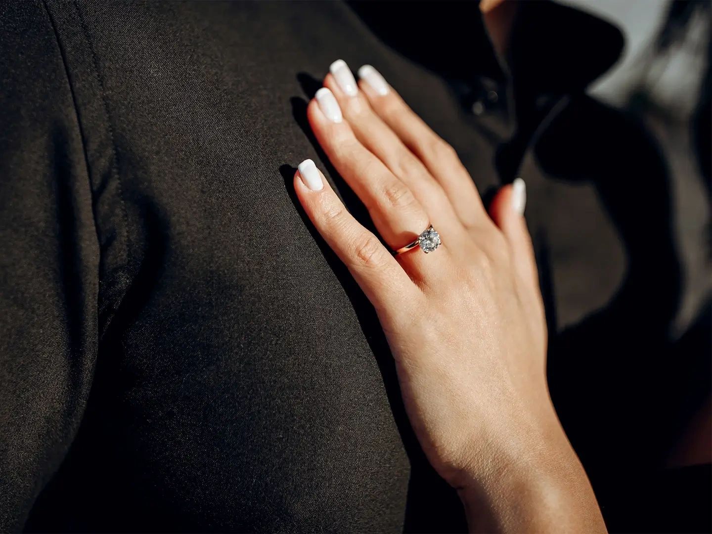 Hand with diamond ring on a black background.