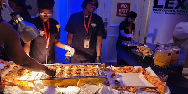 Two people serving catered food.