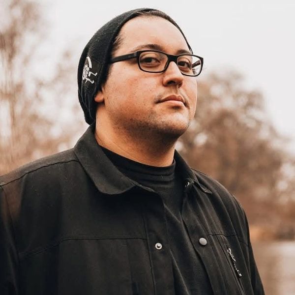 Man wearing glasses and a black beanie outdoors.