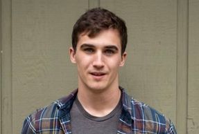 Young man with short brown hair wearing a plaid shirt.