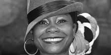 Smiling woman wearing a hat and hoop earrings.