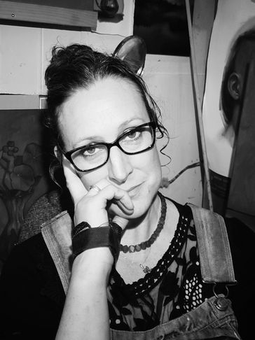 Black and white image of the NZ artist Jonette Murray wearing glasses smiling