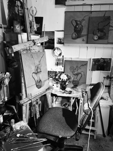 Black and white image of NZartist Jonette Murray's studio with paintings , easel and chair