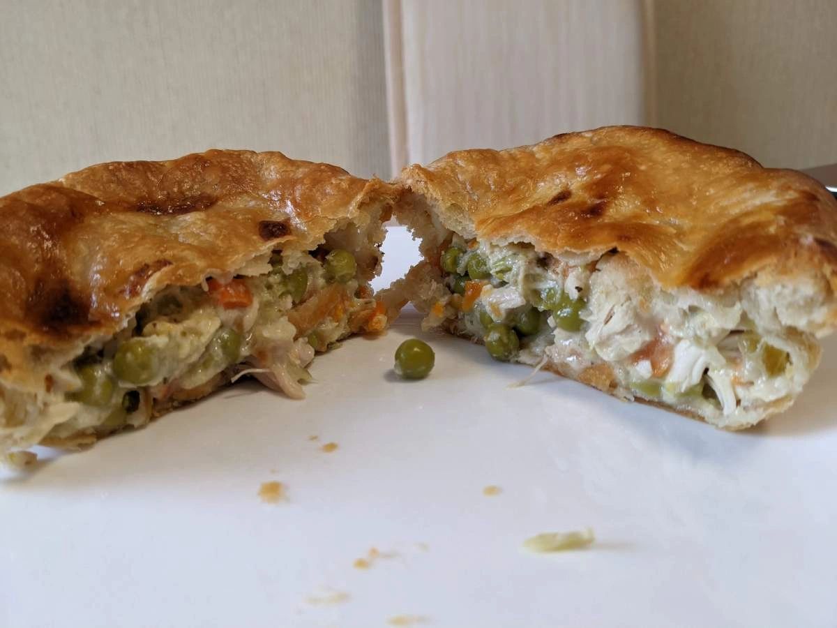 A homemade chicken pot pie sliced in half, revealing a creamy filling with chunks of chicken.