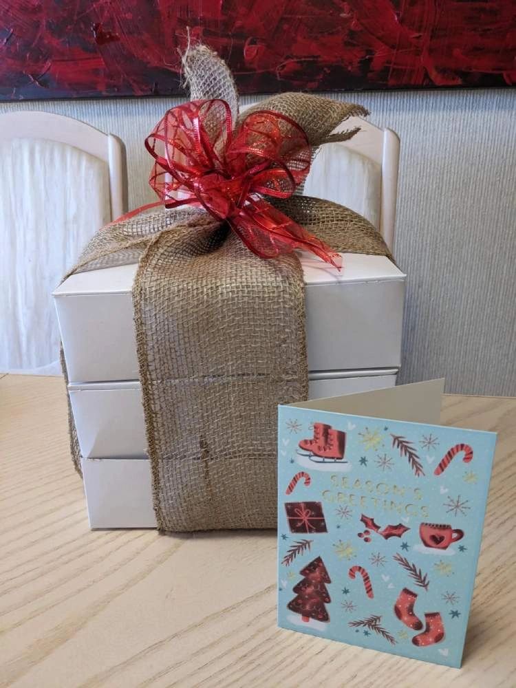 A gift package with 3 pies in white boxes tied with a burlap ribbon & red bow plus a Christmas card.