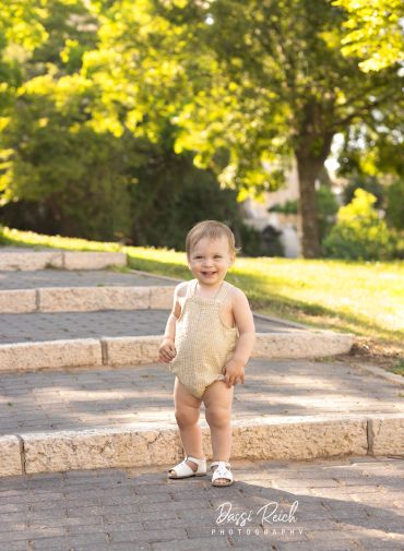 Happy toddler standing outdoors on stone steps.