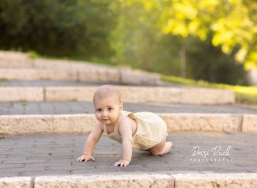 Baby crawling outdoors on a stone pathway.