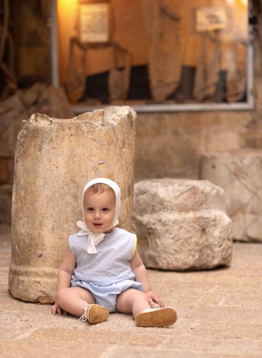 Baby sitting on the floor near ancient stone artifacts.
