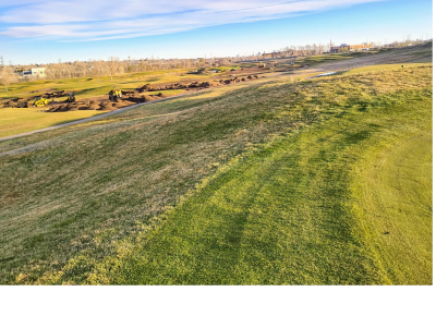 Wide view of a grassy golf course under a clear sky.