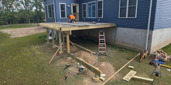 Man building a wooden deck on a house.