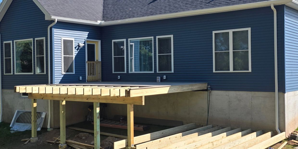 Wooden deck construction in progress on a blue house.