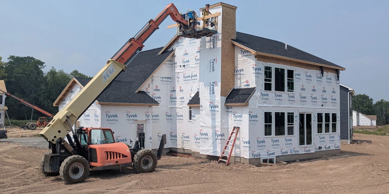 Construction workers wrap a house in Tyvek home wrap.