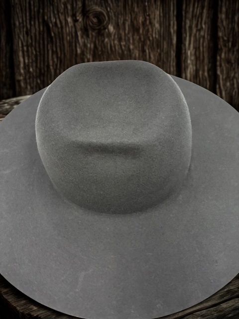 Gray wide-brimmed hat on wooden surface with rustic background.