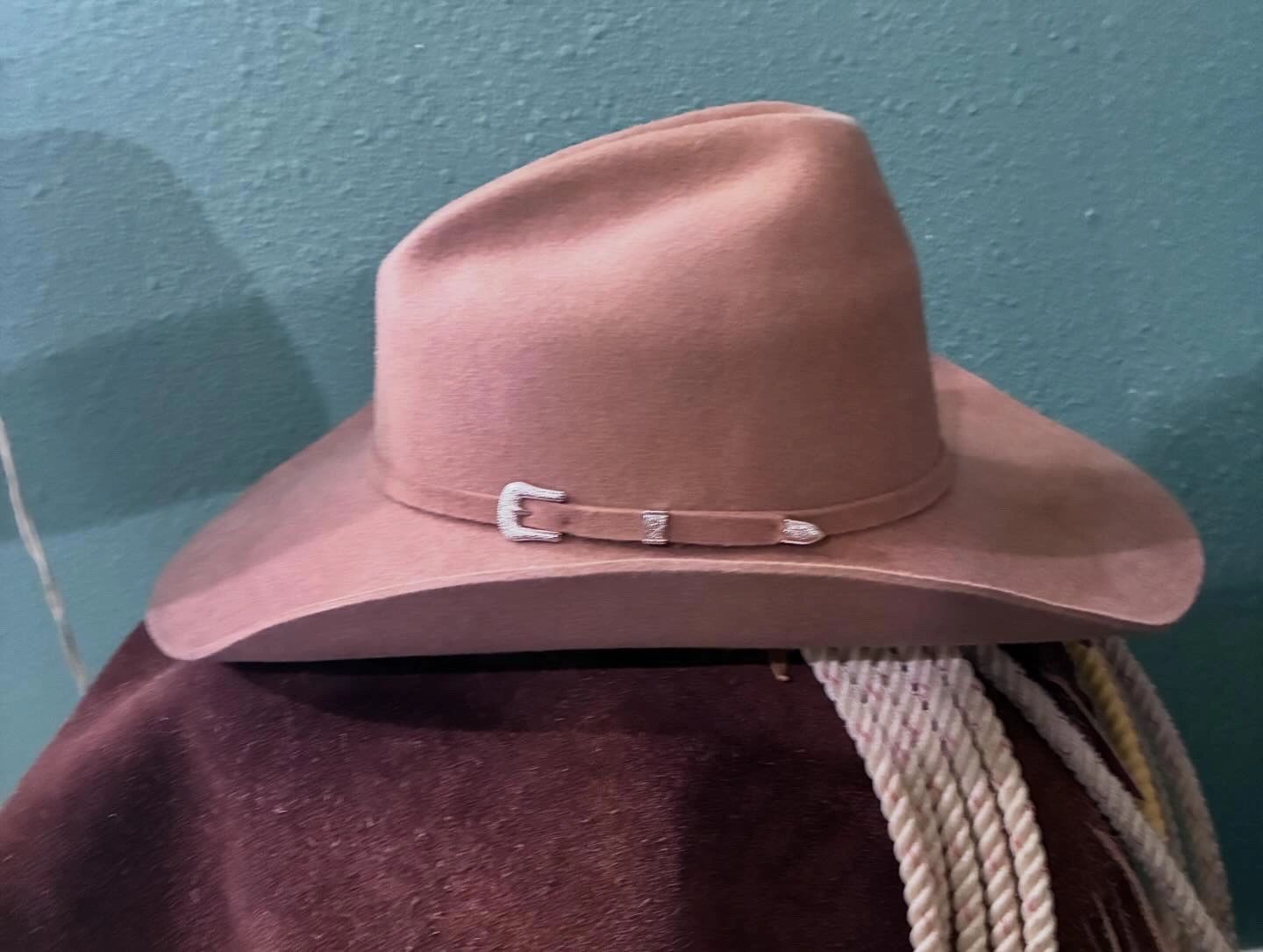 A brown felt cowboy hat with a decorative band and buckle.